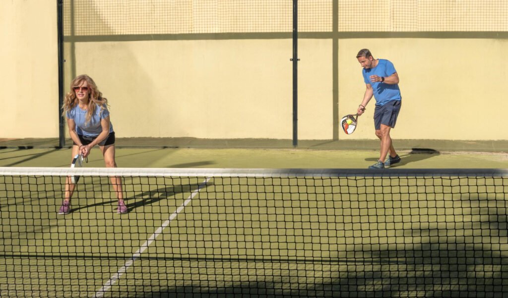 Deux partenaires débutants coordonnant leur placement pendant un échange de padel