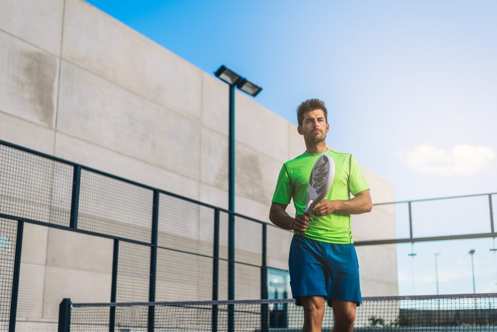 Terrain de padel fermé avec filet, vitres et grilles.