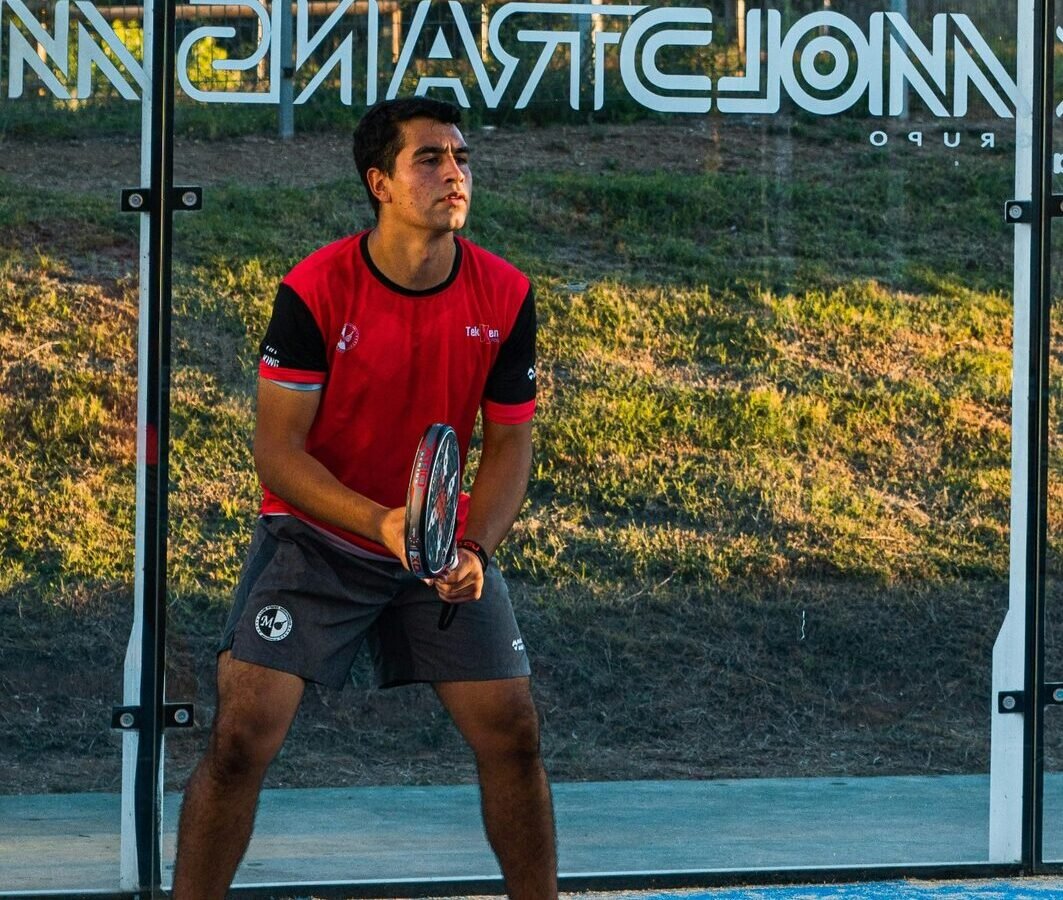 Joueur de padel prêt à recevoir sur une piste