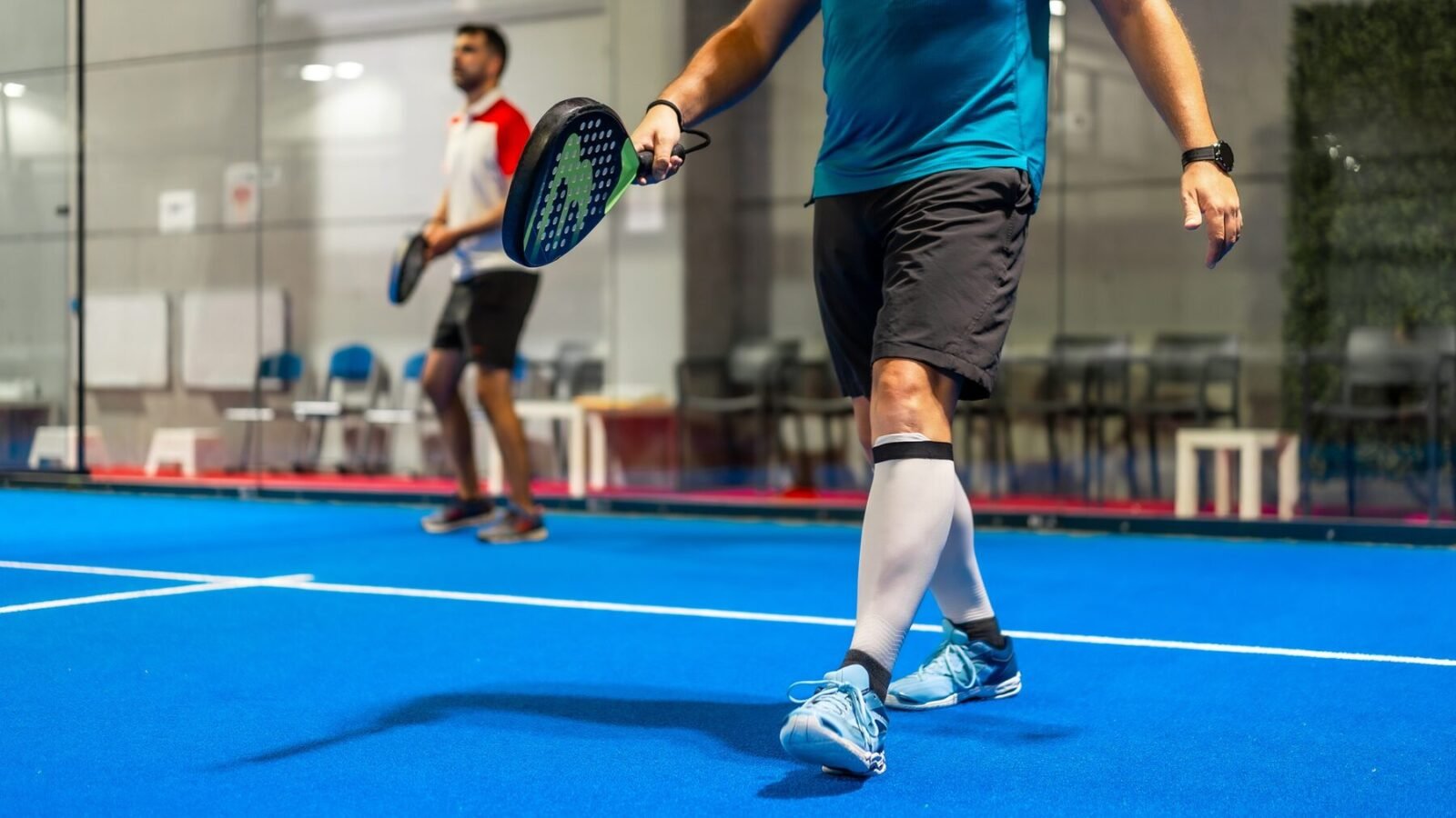 Deux partenaires avec leurs raquettes sur une piste de padel bleue