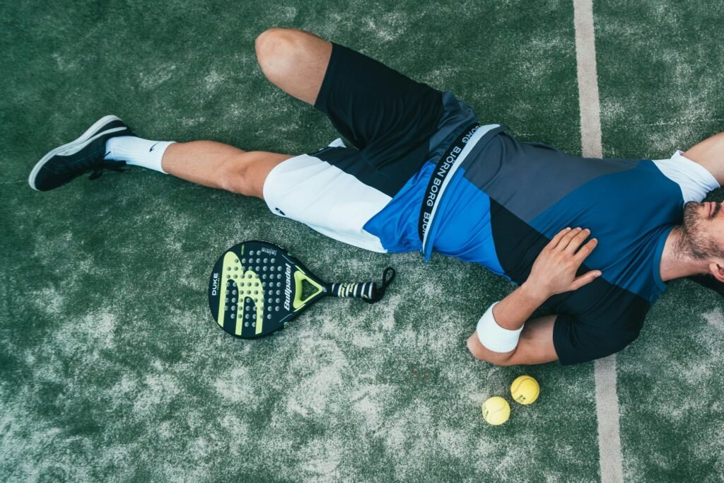 Joueur de padel allongé sur la piste près de sa raquette