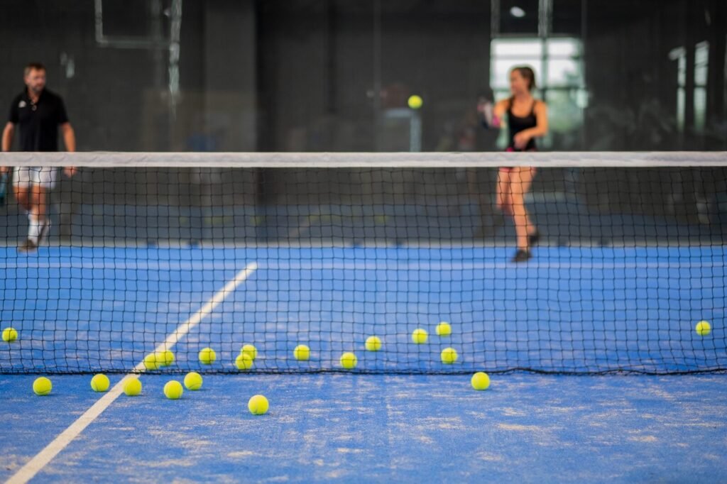 Deux joueurs amateurs échangent sur une piste de padel intérieure