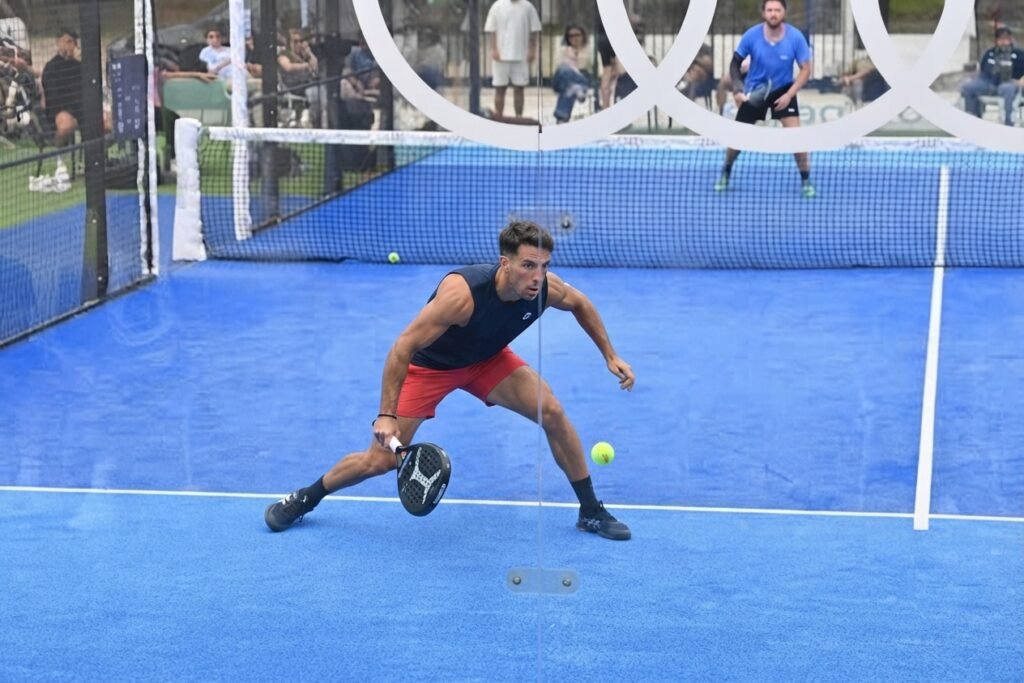 joueur de padel positionné en fond de court devant les vitres